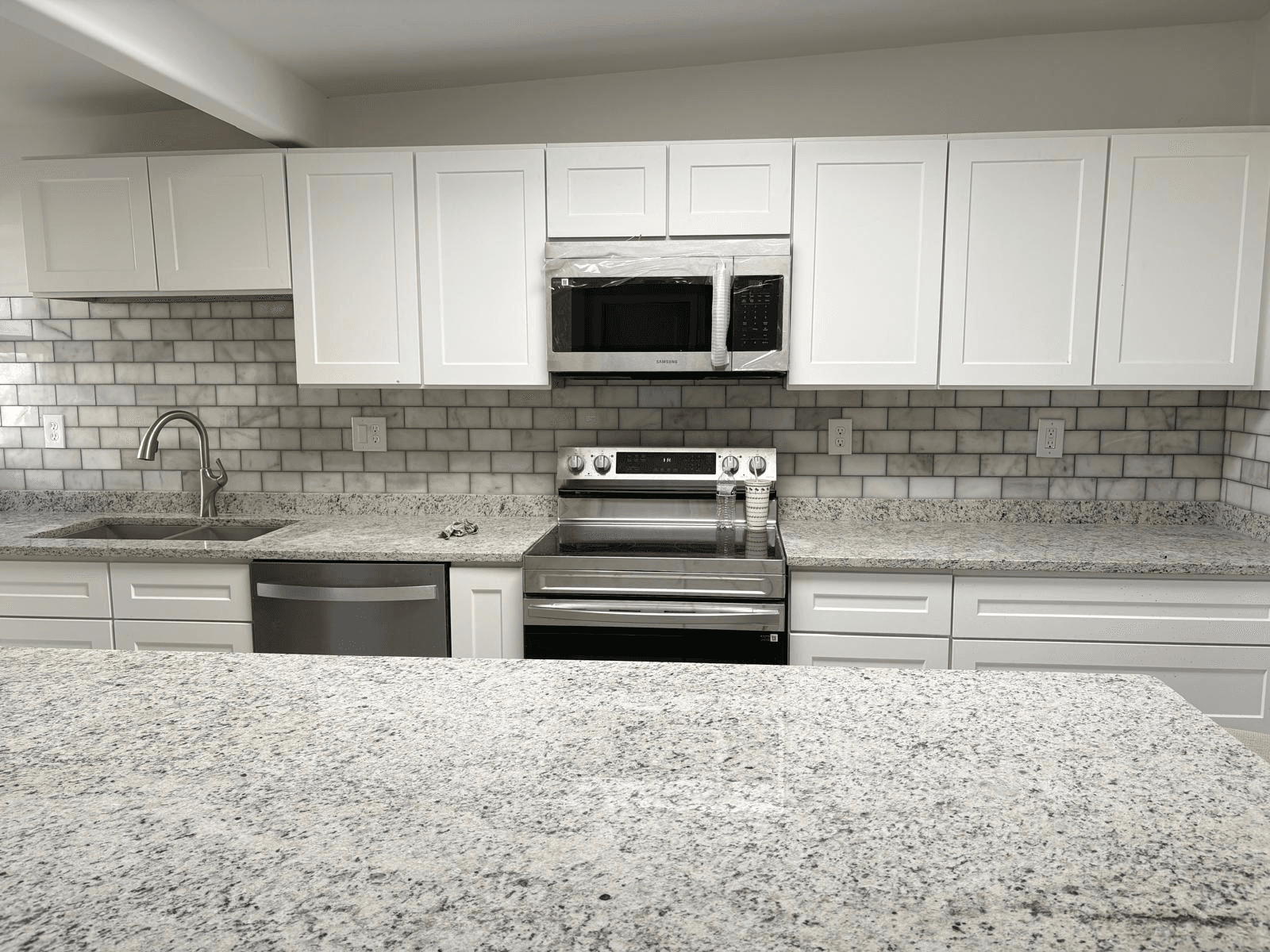 White kitchen with subway tile backsplash and granite counters